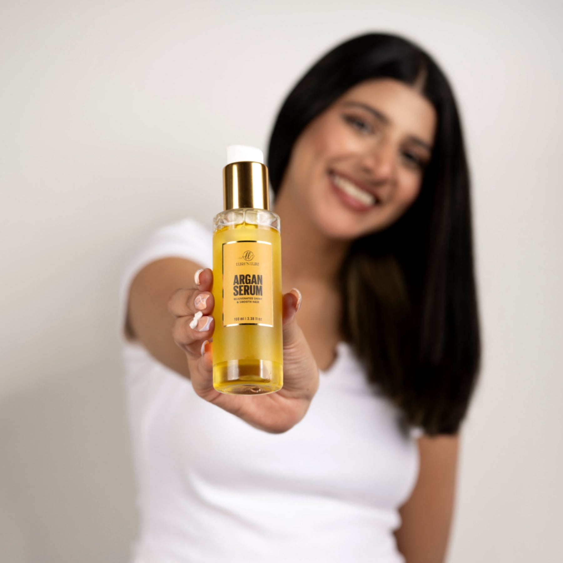 "Model applying LUSHNLURE Argan Serum to her hair, highlighting its smooth, lightweight texture. The serum deeply nourishes and hydrates, leaving hair shiny, soft, and frizz-free with a healthy, natural glow."