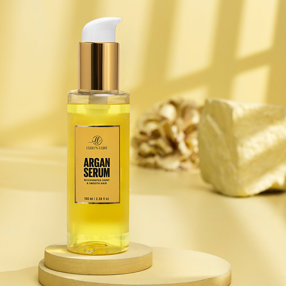 "LUSH 'N LURE Argan Serum bottle elegantly presented with a backdrop of argan nuts and leaves, highlighting its nourishing formula designed to hydrate and soften hair."
